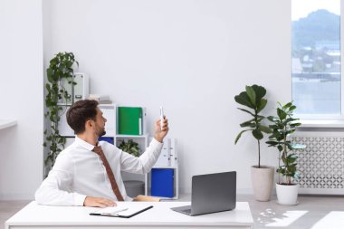 Ofisteki klimayı uzaktan kumandayla kontrol eden adam.