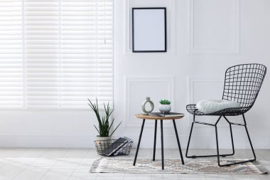 Metal sandalye, yan masa ve dekorasyon beyaz duvarın yanında oturma odasında, mesaj için yer var. İç tasarım