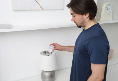 İçerideki şık lambada ampulü değiştiren adam.