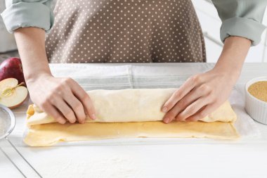 Mutfaktaki beyaz ahşap masada nefis elmalı turta yapan kadın.