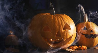 Cadılar Bayramı kutlaması. Kabaklar oyulmuş ürkütücü yüzler ve karanlıkta duman.