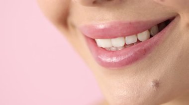 Pembe arka planda güzel dudakları olan gülümseyen kadın, makro manzara.