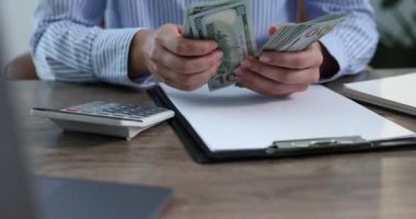 Ahşap masada dolar sayan bir kadın, yakın plan.