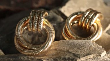 Kayalarda duman içinde zarif altın küpeler, yakın plan.