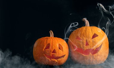 Cadılar Bayramı kutlaması. Ürkütücü balkabağı fenerleri ve siyah arka planda duman.