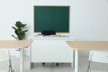 Boş yeşil karatahta, masalar, sandalyeler ve bitkiler sınıfta