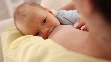 Anne, bebeğini evde emziriyor.