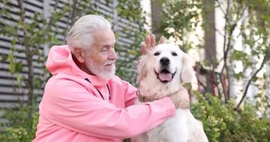 Yaşlı adam dışarıda sevimli Golden Retriever köpeğiyle konuşuyor.