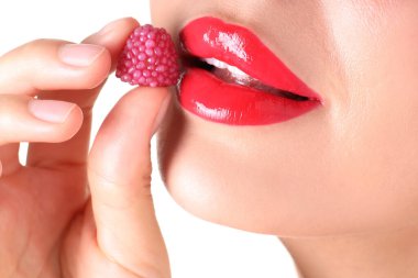 Dudaklarında güzel kırmızı ruj ve beyaz arka planda ahududu şekeri olan kadın, yakın plan.