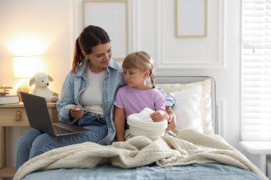 Sağlığınıza. Anne ve hasta kızı evdeki yatağında dizüstü bilgisayarla doktorla görüşüyorlar.