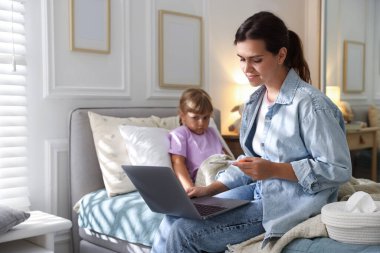 Sağlığınıza. Anne ve hasta kızı evdeki yatakta dizüstü bilgisayarla doktorla görüşüyorlar, seçici bir şekilde.