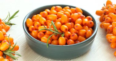 Olgun deniz dikenli üzümleri, yapraklar ve kâse açık ahşap masa, yakın çekim