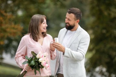 Nişan yüzüklü bir adam kız arkadaşına dışarıda evlenme teklif ediyor.
