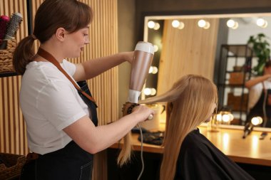Kuaför kuaförde müşterinin saçını kurutuyor.