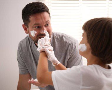 Baba oğul banyoda yüzlerine tıraş köpüğü sürüyorlar.