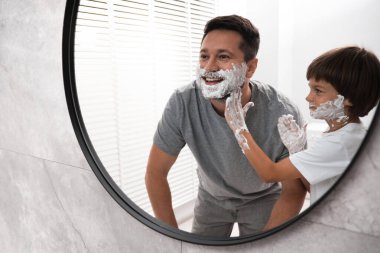 Banyoda yüzlerinde tıraş köpüğü olan baba ve oğul.