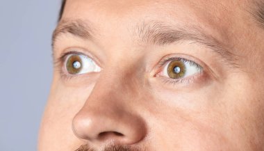 Açık gri arka planda güzel gözleri olan adam, yakın plan.