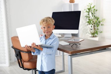 Meslek seçimi. Ofiste dizüstü bilgisayarda çalışıyormuş gibi yapan küçük çocuk.