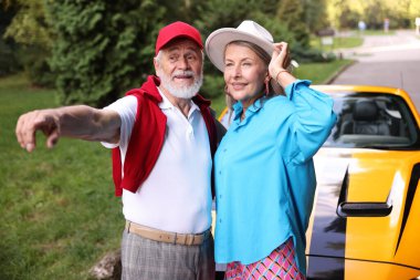 Modern Cabriolet yakınlarında şık bir çift açık havaya bakıyor.