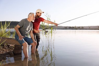 Yaşlı babası ve mutlu oğlu nehirde birlikte balık tutuyorlar.
