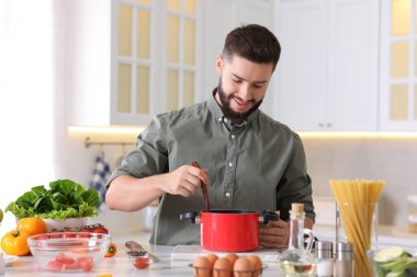 Mutfaktaki masada yemek pişiren gülümseyen adam.