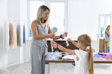 Meslek seçimi. Küçük kız atölyede çalışan annesine yardım ediyor.