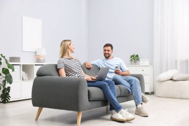 Cihazları olan mutlu çift evdeki kanepede birlikte vakit geçiriyor.