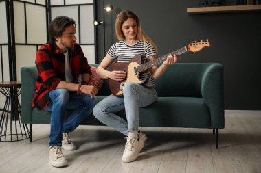 Evdeki kanepede gitar çalmayı öğreten öğretmen.