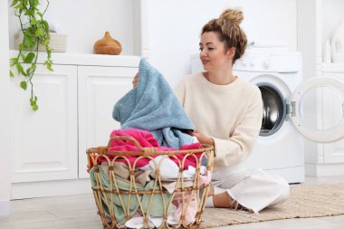 Çamaşır makinesinin yanında çamaşır makinesi olan bir kadın.