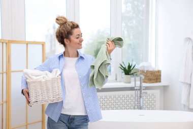 Çamaşır dolu sepeti olan bir kadın, mesaj atmak için yeri var.