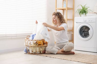 Çamaşır makinesinin yanında çamaşır makinesi olan bir kadın.
