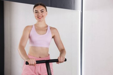 Spor salonundaki aynanın yanındaki trambolinde gülümseyen kadın. Metin için boşluk