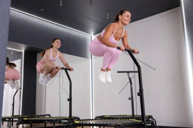 Spor salonundaki trambolinde zıplayan gülümseyen kadınlar, düşük açı.