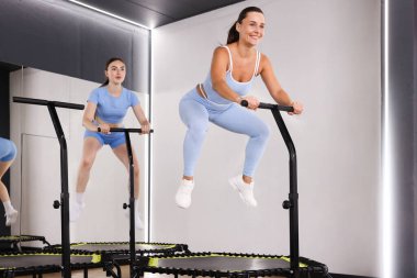 Spor salonundaki mini egzersiz trambolinlerinde zıplayan genç kadınlar, düşük açı.