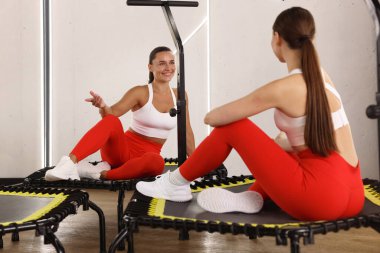 Spor salonundaki trambolinde konuşan gülümseyen kadınlar.