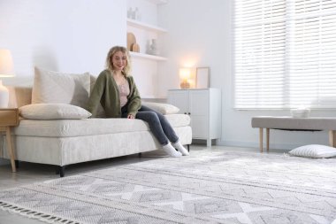 Evdeki kanepede dinlenen mutlu genç kadın, mesaj için yer.