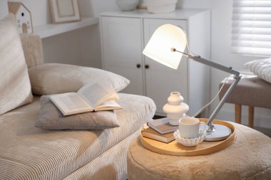 Şık lamba, vazo, kitaplar ve fincanlar kapalı koltuğun yanında.