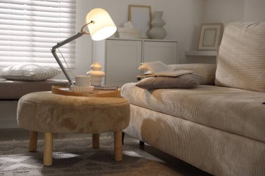 Şık lamba, vazo, kitaplar ve fincanlar kapalı koltuğun yanında.