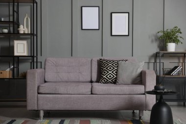 Yumuşak kanepe, yan masa ve oturma odasındaki gri duvarın yanındaki raf ünitesi. İç tasarım