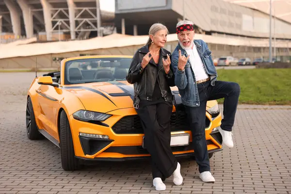Modern Cabriolet yakınlarındaki şık yaşlı çift açık havada kaya jesti sergiliyor.