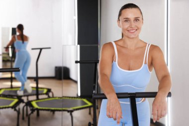 Spor salonundaki aynanın yanındaki trambolinde gülümseyen kadın. Metin için boşluk