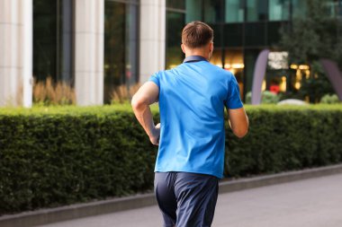 Spor giyimli bir adam dışarıda koşuyor.