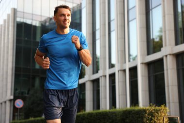 Spor giyimli bir adam açık havada koşuyor. Düşük açılı. Metin için boşluk