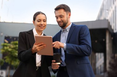 Paket kahve. Açık havada buluşurken kağıt bardak içen bir adam ve iş ortağı.