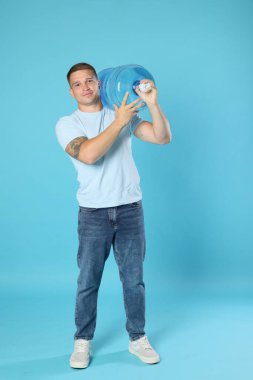 Açık mavi arka planda serin su şişesiyle teslimatçı.