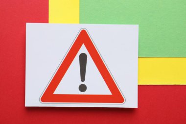 Risk. Renk arkaplanı üzerinde uyarı işareti olan kağıt sayfası, üst görünüm