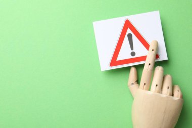 Risk. Yeşil arka planda uyarı işareti olan kağıt parçasına bakan manken eli düz yatıyordu. Metin için boşluk