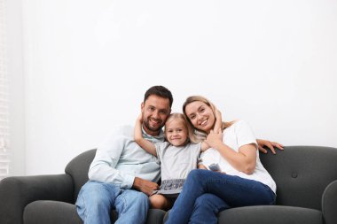 Evdeki kanepede klimalı, uzaktan kumandalı mutlu bir aile.