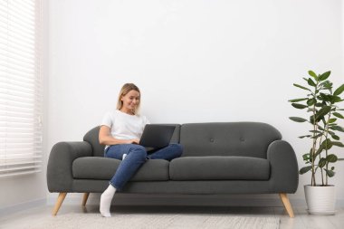 Evdeki kanepede dizüstü bilgisayarı olan kadın. Metin için boşluk