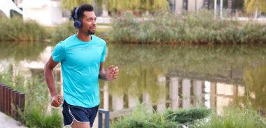 Nehir kenarında çalışan kulaklıklı yakışıklı bir adam. Metin için boşluk